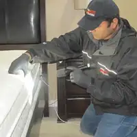 Bed bug inspection technician checking a mattress and bed frame for signs of infestation in Baton Rouge, LA