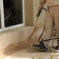 General pest control technician spraying exterior perimeter around a home in Baton Rouge, LA