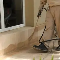 General pest control technician spraying exterior perimeter around a home in Baton Rouge, LA