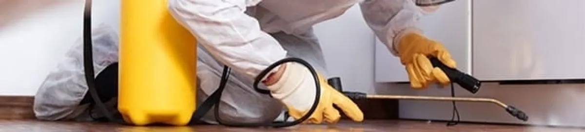 Roach exterminator treating cracks and crevices along kitchen baseboards in Baton Rouge, LA