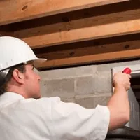 Termite inspection technician checking a basement wall and framing for termite activity in Baton Rouge, LA