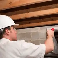 Termite inspection technician checking a basement wall and framing for termite activity in Baton Rouge, LA